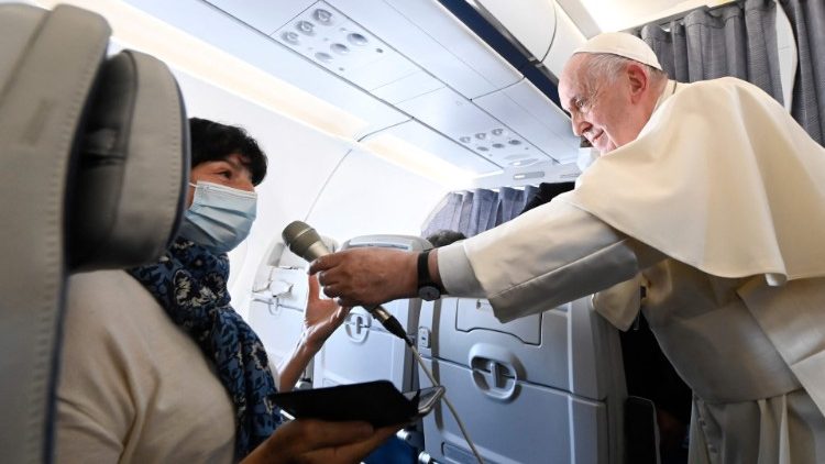 Papst Franziskus reicht einer Journalistin das Mikrophon bei seiner „fliegenden Pressekonferenz" im Dezember 2021