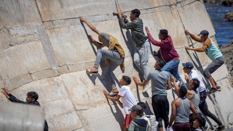 Migantes escalan un malecón en la ciudad norteña de Fnideq después de intentar cruzar la frontera de Marruecos al enclave español de Ceuta en el norte de África