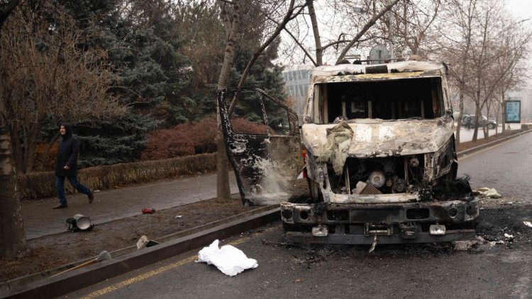 A pedestrian walks past a burnt-out fire engine in central Almaty