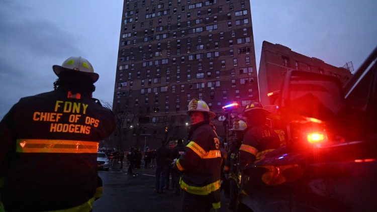 Firefighters work outside an apartment building after a deadly fire in the Bronx