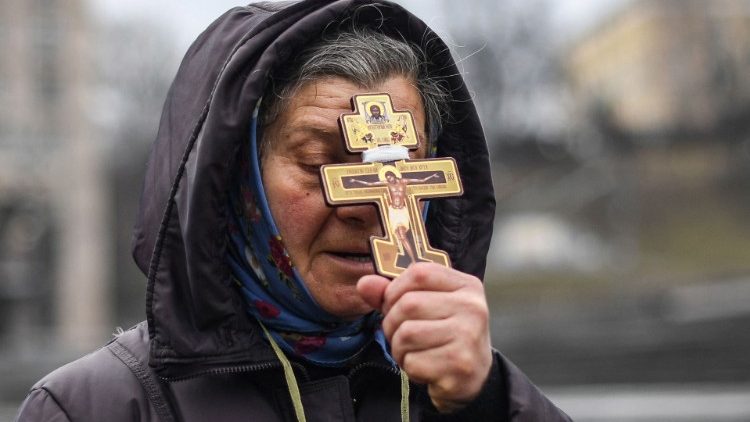 यूक्रेन के कीव शहर में पवित्र क्रूस हाथ में लिए प्रार्थना करते हुए 