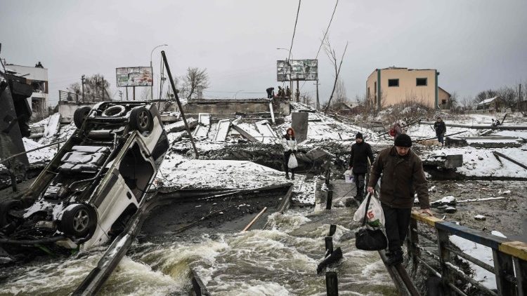 Civilians cross a river on a blown up bridge in Kyiv