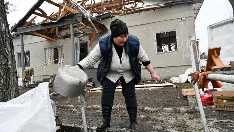 युक्रेन के ब्रोवारी में अपने टूटे घर के सामने खड़ी महिला