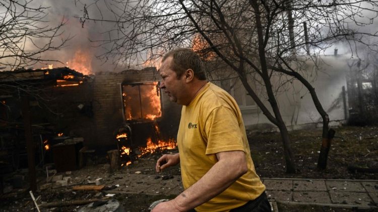A resident of the city of Irpin runs from his burning house after being shelled