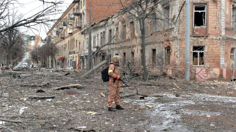 Um membro das Forças de Defesa Territoriais da Ucrânia observa as destruições após um bombardeio na segunda maior cidade da Ucrânia, Kharkiv. (Photo by Sergey BOBOK / AFP)