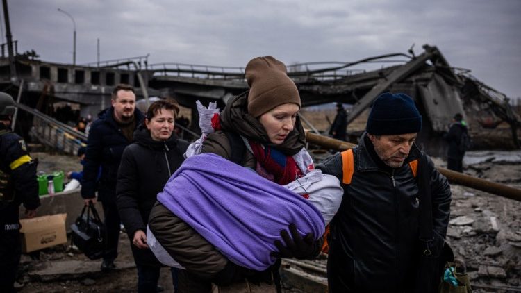 Una mujer con su bebé cruza un puente destruido mientras huyen de la ciudad de Irpin, al noroeste de Kiev, el 7 de marzo de 2022.