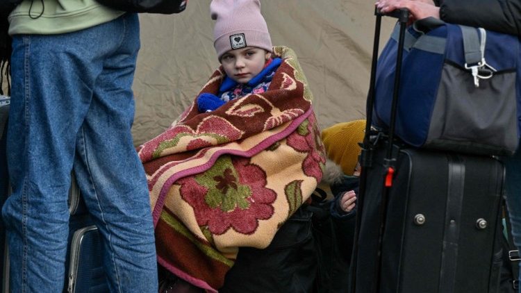 Una niña descansa sobre unas maletas en un cruce fronterizo