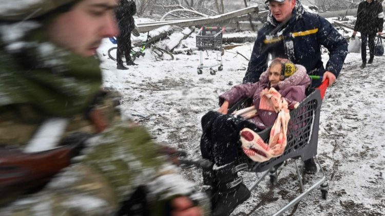 A rescuer pushes a trolley carrying an elderly woman during the evacuation of civilians from the city of Irpin, northwest of Kyiv
