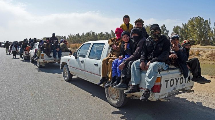 Migrantes afganos viajan en camionetas por una carretera desértica 