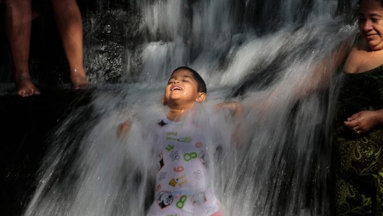 Bambino che fa un bagno in una cascata