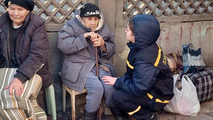 Nesta foto tirada e divulgada pelo Serviço de Emergência do Estado da Ucrânia em 16 de março de 2022, um psicólogo de emergências ucraniano ajuda uma idosa evacuada de um prédio residencial danificado por bombardeios em Kiev.