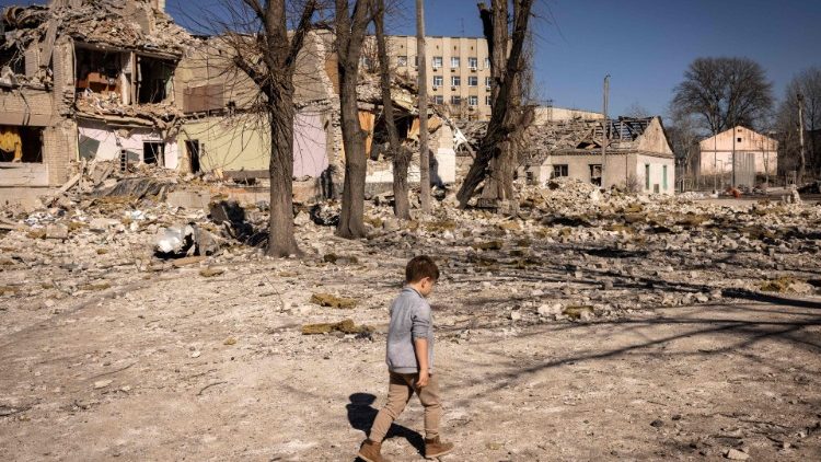 Ein Kind vor einer zerstörten Schule im ukrainischen Schytomyr