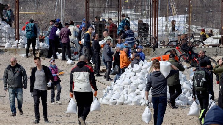 Moradores locais carregam sacos cheios de areia enquanto constroem uma barricada para um posto de controle em Odessa em 25 de março de 2022, em meio à invasão russa da Ucrânia. (Foto de Oleksandr GIMANOV/AFP)