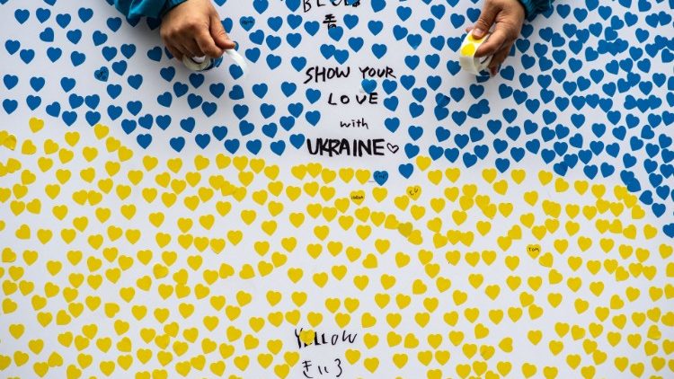 Uma placa é vista com adesivos em forma de coração nas cores da bandeira ucraniana enquanto as pessoas participam de uma manifestação de arrecadação de fundos para apoiar a Ucrânia no distrito de Shinjuku, em Tóquio.  (Foto de Philip FONG / AFP)