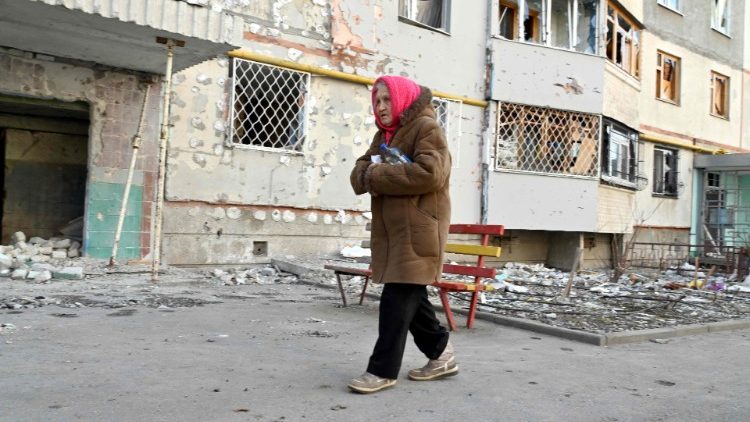 Uma idosa caminha em frente ao seu prédio residencial em Kharkiv em 29 de março de 2022, parcialmente destruído por um bombardeio de tropas russas, no 34º dia da invasão russa da Ucrânia. - A Ucrânia está pedindo um "acordo internacional" para garantir sua segurança, que seria assinado por vários países garantidores, disse em 29 de março de 2022 o negociador-chefe ucraniano após várias horas de conversas russo-ucranianas em Istambul. (Foto de Sergey BOBOK/AFP)