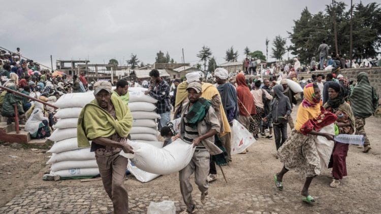 Homens carregam um saco de trigo durante uma distribuição de alimentos do Programa Mundial de Alimentos (PMA) para deslocados internos (IDP) em Debark, a 90 quilômetros da cidade de Gondar, na Etiópia. (Foto de Amanuel Sileshi/AFP)