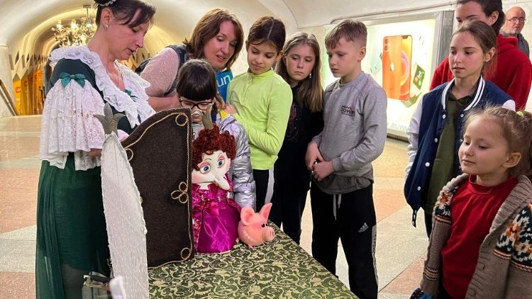 Crianças assistem a marionetista Oleksandra Shlykova (esquerda) enquanto ela se apresenta nas estações de metrô de Kharkiv, leste da Ucrânia, em 16 de abril de 2022. para um bando de crianças encantadas. Com um elenco de bonecos caricaturais, incluindo um rei bigodudo e uma manada de porcos, Oleksandra Shlykova e Anton Andriushchenko contam a história de como "as princesas são diferentes", encantando as crianças e seus pais. (Foto de Maryke VERMAAK / AFP)