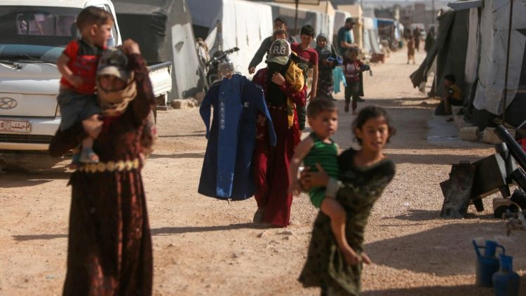 Kinder in einem Flüchtlingslager kehren mit gespendeten Kleidungsstücken in ihre Notunterkünfte zurück