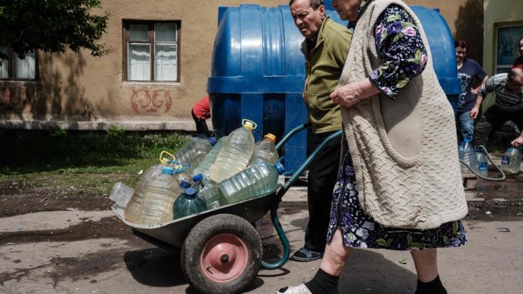 Los residentes llevan botellas de agua en una carretilla tras llenarlas en un tanque de suministro de agua en Toretsk, Ucrania, 