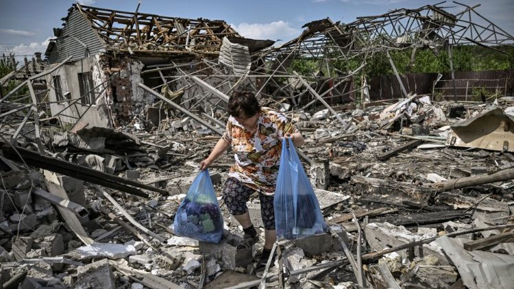 A woman gathers belongings from her destroyed home in Slovyansk