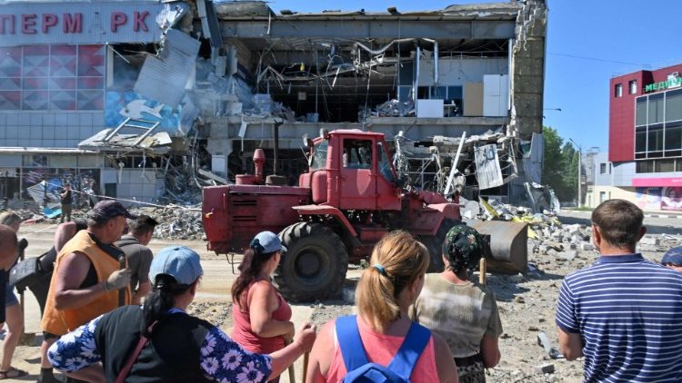 Trabajadores municipales limpian los escombros de un supermercado, parcialmente destruido por un ataque con misiles en las afueras del sureste de la ciudad ucraniana de Járkiv el 8 de junio