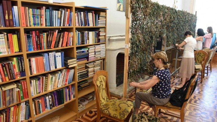 Voluntários tecem redes de camuflagem para militares ucranianos em uma biblioteca na cidade de Lviv, no oeste da Ucrânia, em 9 de junho de 2022. (Foto de Yuriy Dyachyshyn / AFP)