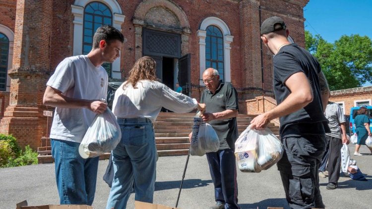 Voluntários distribuem ajuda humanitária às pessoas no pátio da Igreja Ortodoxa de São João, o Teólogo, em Kharkiv, em 10 de junho de 2022. (Foto de SERGEY BOBOK / AFP)