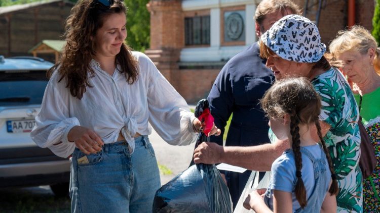 Voluntários distribuem ajuda humanitária às pessoas no pátio da Igreja Ortodoxa de São João, o Teólogo, em Kharkiv, em 10 de junho de 2022. (Foto de SERGEY BOBOK / AFP)