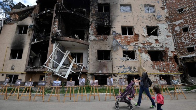 Uma mulher e sua filha passam por um prédio residencial destruído como resultado de um bombardeio na cidade de Irpin, perto da capital ucraniana de Kyiv, em 16 de junho de 2022, quando a guerra russo-ucrânia entra em seu 113º dia. (Foto de Sergei CHUZAVKOV/AFP)