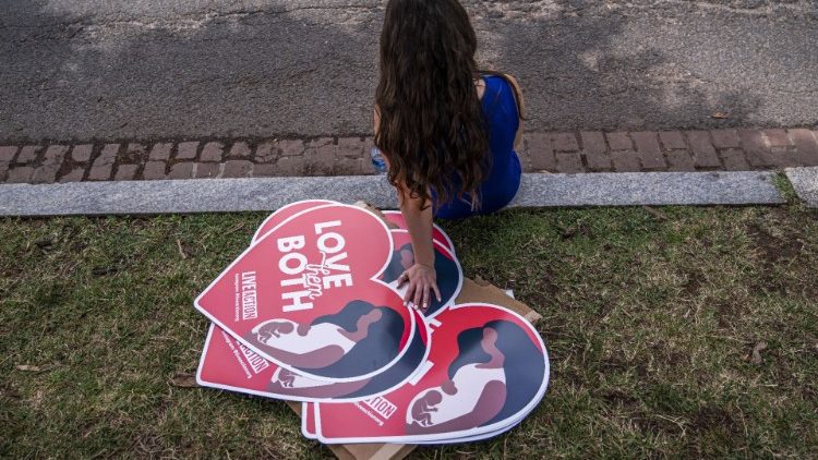 A woman sits near the Supreme Court with pro-life posters