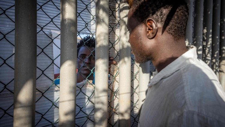 Zwei Männer unterhalten sich am Zaun eines Auffanglagers in Melilla