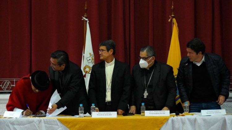 Leonidas Iza (L) signs a document next to the Secretary General of Ecuador's Bishops' Conference, Bishop David de la Torre, as Conference president Archbishop Luis Cabrera and Minister of Government Francisco Jimenez look on.