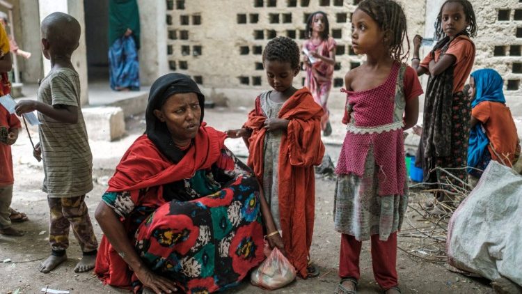 Medina Ahmed, deslocada de Konaba, senta-se ao lado de crianças em um complexo de prédios abandonados que abriga deslocados, perto da cidade de Dubti, a 10 quilômetros de Semera, na Etiópia. Mais de um milhão de pessoas precisam de ajuda alimentar na região de acordo com o Programa Alimentar Mundial. (Foto de EDUARDO SOTERAS/AFP)
