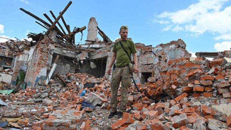 Um militar ucraniano inspeciona as ruínas do prédio do Liceu, que se suspeita ter sido destruído após um ataque com mísseis perto de Kharkiv em 5 de julho de 2022, em meio à invasão russa da Ucrânia. (Foto de SERGEY BOBOK/AFP)