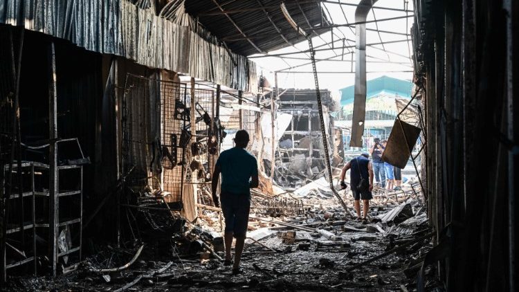 Pessoas caminham pelos danos causados ao mercado central em Sloviansk por um suposto ataque com mísseis, em 6 de julho de 2022, em meio à invasão russa da Ucrânia. (Foto de MIGUEL MEDINA/AFP)