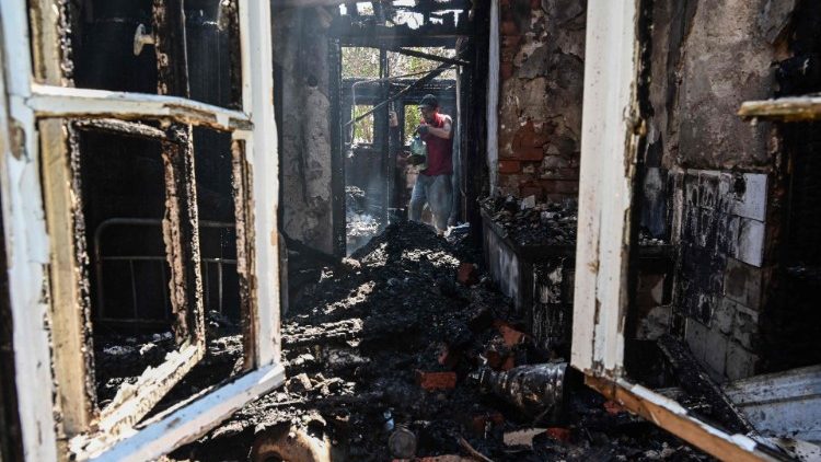 Maksym Sologubon, 36 anos, apaga fogo na casa de sua avó após um ataque aéreo noturno nos subúrbios no noroeste de Sloviansk, em 12 de julho de 2022 (Foto de Miguel Medina/AFP)