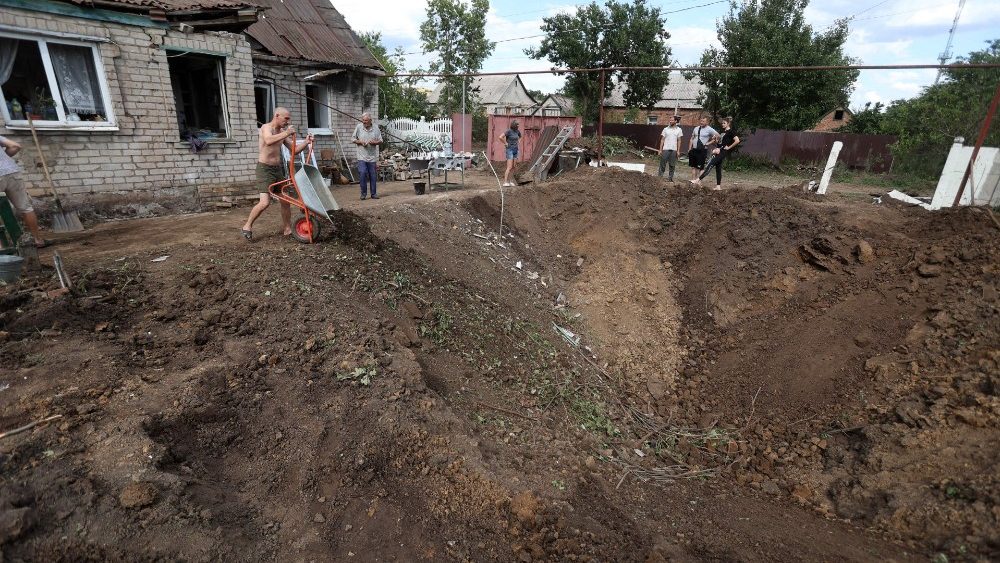 Moradores locais jogam destro?os em uma cratera aps um ataque russo em Kostyantynivka, regi?o de Donetsk, em 13 de julho de 2022. (Foto de Anatolii Stepanov / AFP)