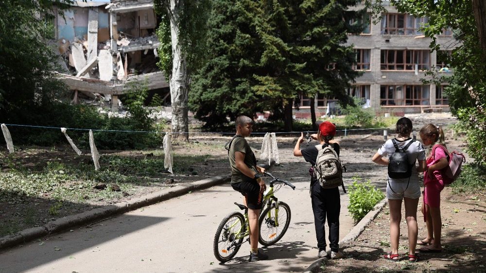 Crian?as observam sua escola parcialmente destruda por suposto bombardeio russo em Kostyantynivka, regi?o de Donetsk, em 13 de julho de 2022. (Foto de Anatolii Stepanov / AFP)