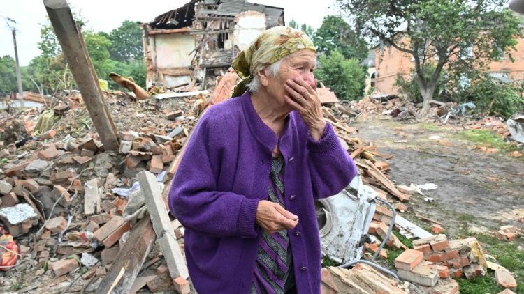 Uma moradora local, Raisa Kuval, 82, reage ao lado de um prédio danificado parcialmente destruído após um bombardeio na cidade de Chuguiv, leste de Kharkiv, em 16 de julho de 2022. - Na região nordeste em torno da segunda cidade da Ucrânia de Kharkiv, o governador Oleg Synegubov disse que um ataque de mísseis russo durante a noite matou três pessoas na cidade de Chuguiv. (Foto de SERGEY BOBOK/AFP)