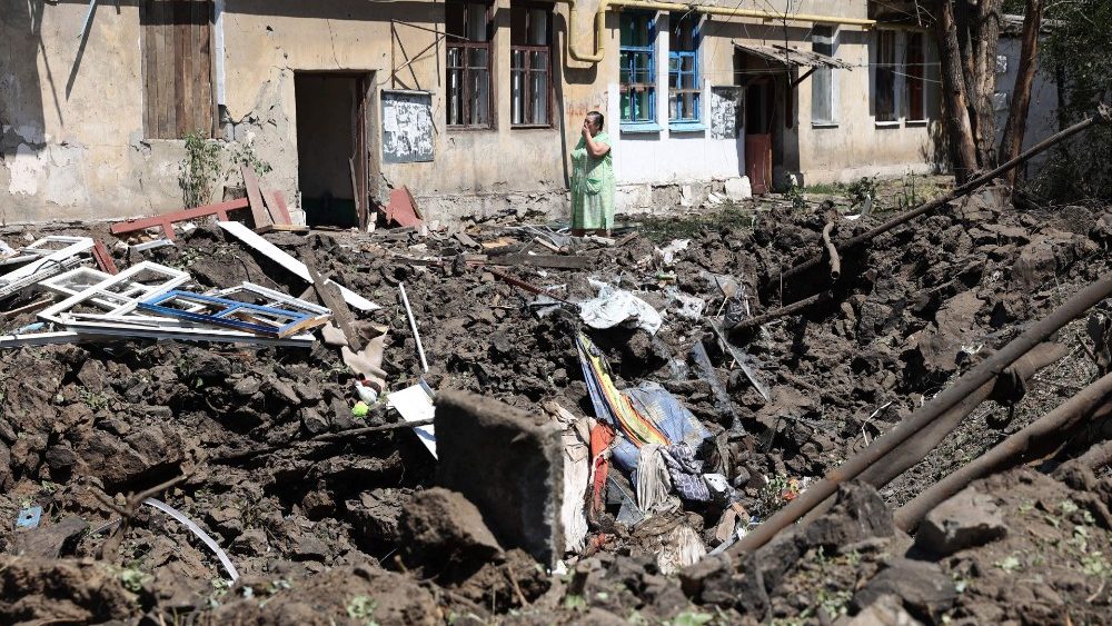 Uma mulher rchora ao lado de uma cratera causada por bombardeios russos do lado de fora de sua casa na cidade de Toretske, na regi?o de Donetsk, em 17 de julho de 2022. (Foto de Anatolii Stepanov / AFP)