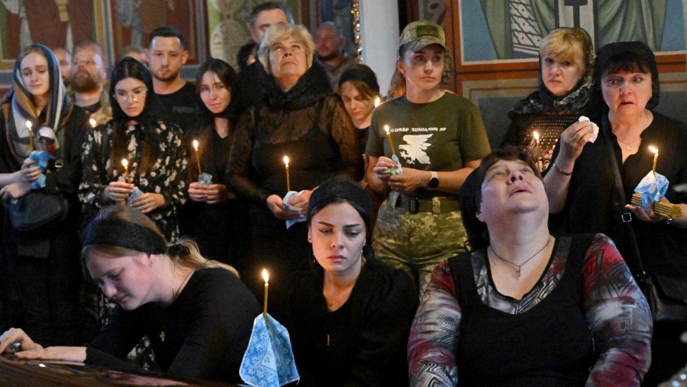 Familiares choram ao lado do caix?o do oficial ucraniano apelidado Fanat durante seu funeral em uma igreja em Kyiv em 18 de julho de 2022. - A Rssia invadiu a Ucr?nia em 24 de fevereiro de 2022. (Foto de Sergei SUPINSKY / AFP)