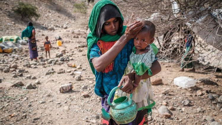 Deslocada interna devido à guerra na Etiópia, lava a face de sua filha no povoado de Erebti