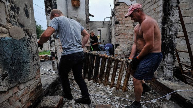 Voluntários limpam os escombros de uma casa destruída como resultado do bombardeio na cidade de Chernihiv em 20 de agosto de 2022, em meio à invasão da Ucrânia pela Rússia. - A retirada da Rússia de Chernihiv em abril, após um ataque de um mês deixou para trás uma cidade devastada que a Ucrânia precisará de ajuda externa maciça e muitos anos de trabalho para restaurar. (Foto de SERGEI CHUZAVKOV/AFP)