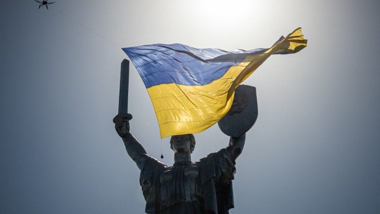 Um drone com uma bandeira nacional ucraniana gigante passa sobre o monumento da Pátria durante o Dia da Independência da Ucrânia em 24 de agosto de 2022, em meio à invasão russa da Ucrânia. (Foto de Dimitar DILKOFF/AFP)