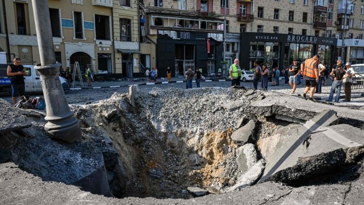 Trabalhadores municipais olham cratera provocada por míssil russo em Kharkiv, em 27 de agosto de 2022. AFP/Sergey Bobok 