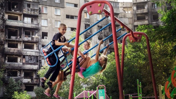 Crianças brincam em frente a prédio bombardeado em Mariupol, 29 de agosto de 2022. (Photo by Stringer)