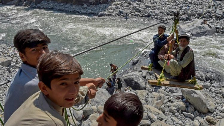 Moradores locais usam um serviço temporário de berço para cruzar o rio Swat após fortes chuvas na cidade do Bahrein do vale de Swat, na província de Khyber Pakhtunkhwa, em 31 de agosto de 2022. (Photo by Abdul MAJEED / AFP)