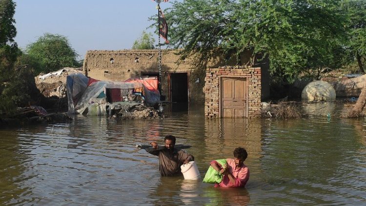 Paquistaneses carregam pertences em meio à água em Shikarpur, província de Sindh, em 31 de agosto de 2022. AFP/Asif Hassan