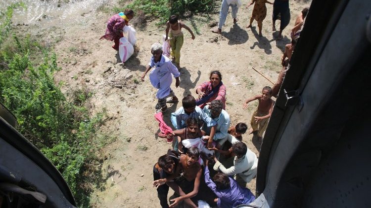Pessoas afetadas pelas enchentes brigam por sacos de comida distribuídos de um helicóptero pelo exército paquistanês no distrito de Dadu, na província de Sindh, em 1º de setembro de 2022. (Photo by Husnain ALI / AFP)