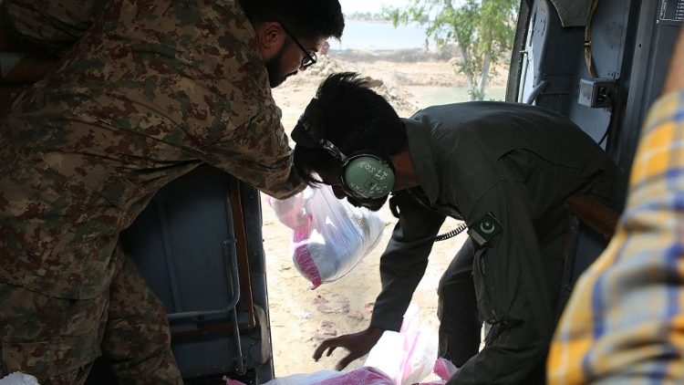 Oficiais do exército paquistanês distribuem sacolas de alimentos de um helicóptero para pessoas afetadas pelas enchentes no distrito de Dadu, na província de Sindh, em 1º de setembro de 2022. (Photo by Husnain ALI / AFP)
